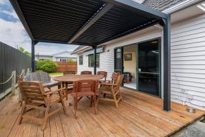 a patio with a table and chairs on a deck at Atarau Grove Holiday House in Paraparaumu