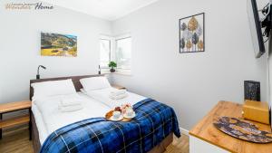 a bedroom with a bed with a blue plaid blanket at Apartamenty z balkonami, blisko wyciągów i centrum in Karpacz