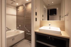 a bathroom with a sink and a tub and a shower at ALPHABED INN Hakata station front in Fukuoka