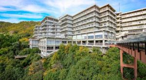 un grand bâtiment au sommet d'une colline avec un train dans l'établissement Ooedo Onsen Monogatari Minoh Kanko Hotel, à Minoh