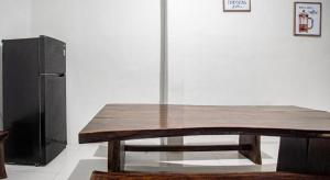 une table en bois dans une pièce avec un réfrigérateur dans l'établissement Hotel O Almahyra Guest House Syariah, à Sultan Thaha Airport