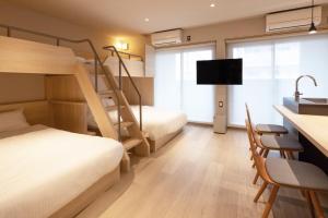 a room with two bunk beds and a desk and a kitchen at ALPHABED INN Hakata station front in Fukuoka