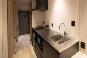 a kitchen with a stainless steel sink and a hallway at ALPHABED INN Hakata station front in Fukuoka +40 photos