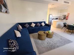 a living room with a blue couch and a kitchen at 5 bedroom Villa - Dubai Hills in Dubai