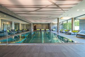 a swimming pool in a hotel lobby with couches at Ritzenhof - Hotel und Spa am See 4-Sterne-Superior in Saalfelden am Steinernen Meer