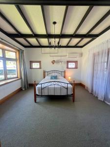 Un dormitorio con una cama en una habitación con ventanas. en Chic 4 bedroom City Home with large Garden, en Palmerston North