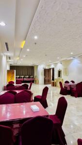 een grote kamer met rode stoelen en een tafel met stoelen bij فندق منازل الحجاز شقق وغرف فندقية in Al ‘Azīzīyah