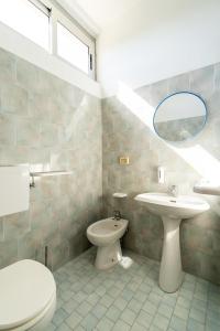 a bathroom with a sink and a toilet and a mirror at Meet Hostel Cervia in Cervia