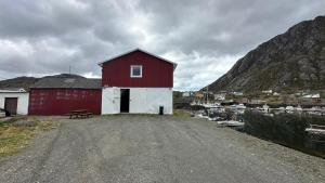 a red and white building next to a body of water at Damperiholmen Apartment, Lofoten in Sund
