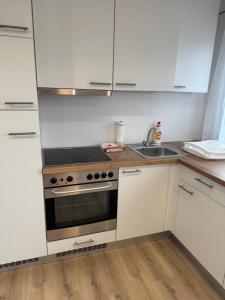 eine Küche mit weißen Schränken und einem Herd und einer Spüle in der Unterkunft Napfény Apartman in Marcali + 8 Fotos