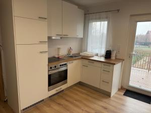 eine Küche mit weißen Schränken, einem Herd und einem Fenster in der Unterkunft Napfény Apartman in Marcali