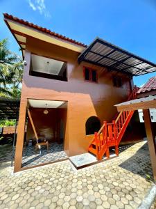 a house with a patio and a staircase in front at Gifal Surf Camp & Cottage in Wainapal