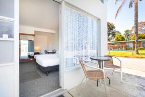 Un dormitorio con una cama y una mesa y sillas. en Ship Inn Motel Yarram, en Yarram