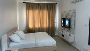 a bedroom with a white bed and a television at Lakowe Lakes Apartment, 2 Bedrooms in Ajibade