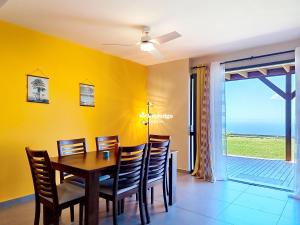 een eetkamer met gele muren en een tafel en stoelen bij Bleu des Ô - Maison de 66m2 avec jacuzzi et sauna in Sainte-Marie +5 foto's