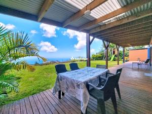 een tafel en stoelen op een terras met uitzicht op de oceaan bij Bleu des Ô - Maison de 66m2 avec jacuzzi et sauna in Sainte-Marie