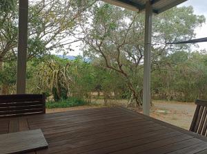a porch with a wooden table and chairs and trees at Studio à Tamaon - Malima Lodge in Pouembout