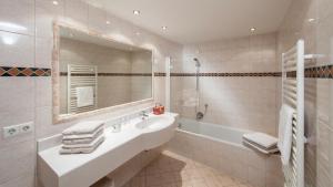 a bathroom with a sink and a tub and a mirror at Appartementhaus Leitner in Ehrwald