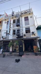 Ein schwarzer Hund liegt vor einem Gebäude in der Unterkunft SB LODGE TAGUIG in Manila