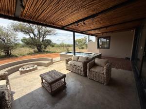 a patio with two chairs and a table and a tub at Blessed Lodge at Ingilozi Mabalingwe in Warmbaths