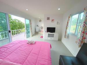 ein Schlafzimmer mit einem rosa Bett und einem TV in der Unterkunft วิวดี รีสอร์ท เขาค้อ in Ban Tha Phon