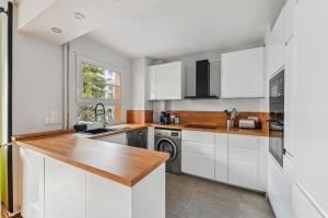 eine Küche mit weißen Schränken und einer Spüle in der Unterkunft Le Sportif - Montrouge in Montrouge