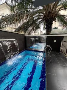 a swimming pool with a waterfall and a palm tree at Urban Muse in Lekki