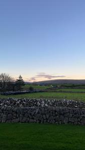 a stone wall in a field with green grass at Kilohill House in Ballyvaughan