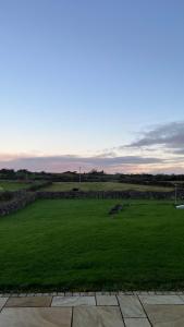 a large green field with a stone wall at Kilohill House in Ballyvaughan