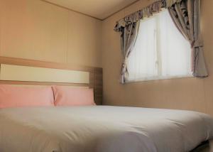 ein Schlafzimmer mit einem weißen Bett und einem Fenster in der Unterkunft Golden Anchor Caravan Park in Chapel Saint Leonards