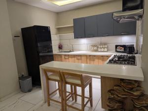 拉瓦尔品第Luxurious 2 Bed Apartment Bahria Active的厨房配有带2把凳子和炉灶的台面