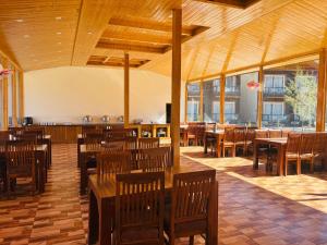 Un restaurante vacío con mesas y sillas de madera. en Shivalaya Retreat - A River Side Resort, en Manali