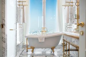 a bath tub in a bathroom with a window at The Bentley Luxury Hotel & Suites in Doha