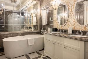 a bathroom with a tub and two sinks and mirrors at The Bentley Luxury Hotel & Suites in Doha