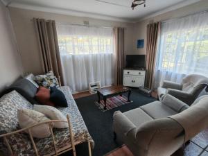 a living room with a couch and chairs and a tv at Coral Cottage in Hilton