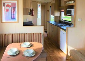 eine kleine Küche mit einem Tisch mit Tellern darauf in der Unterkunft Golden Anchor Caravan Park in Chapel Saint Leonards