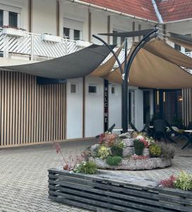 un edificio con un patio con flores y una sombrilla en Hotel Rittinger, en Bonyhád