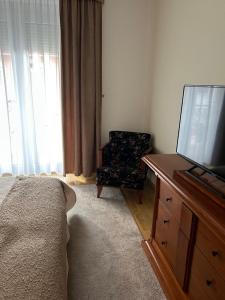Un dormitorio con una cama, un televisor y una silla. en Hotel Rittinger, en Bonyhád