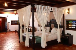 Un dormitorio con una cama con dosel y cortinas blancas. en SVS Arena, en Kodali