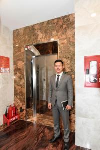 a man in a suit and tie standing in front of a shower at Hùng Anh Hotel in Phan Thiet