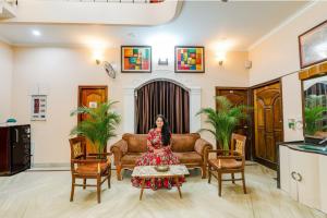 une femme dans un salon avec un canapé et une table dans l'établissement FabHotel Raka Inn, à Allahābād