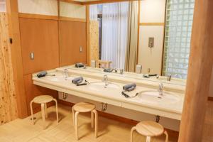 een badkamer met twee wastafels en een grote spiegel bij クラフトホテルあば村 in Wada +33 foto's