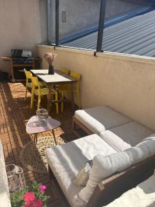 eine Terrasse mit einem Sofa und einem Tisch und Stühlen in der Unterkunft Agréable maison de ville avec terrasse et garage in Saint-Affrique