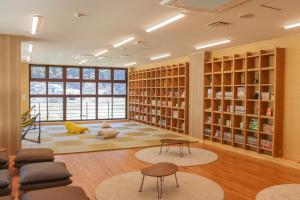 een bibliotheek met boekenkasten en tafels en stoelen bij クラフトホテルあば村 in Wada