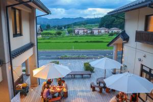 een groep mensen die op een balkon zitten met parasols bij クラフトホテルあば村 in Wada