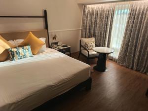 ein Schlafzimmer mit einem Bett, einem Stuhl und einem Fenster in der Unterkunft Romance Resort Varkala in Varkala