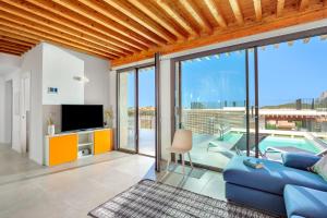 een woonkamer met een blauwe bank en een tv bij Villa Mathis - by And service in Casa Tamponi