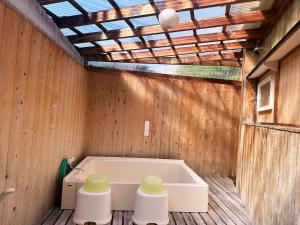 eine Badewanne in einem Zimmer mit einer Holzwand in der Unterkunft やどかり852 in Manazuru
