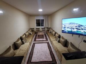 a living room with a large couch and a flat screen tv at Appartement a Louer Laayoune in Laayoune