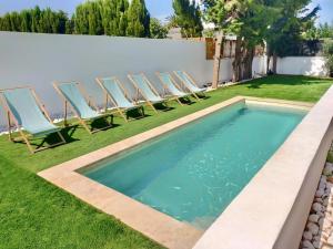 een rij stoelen en een zwembad in de tuin bij Apartaments Gorgot in Empuriabrava